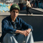 Teenager Junge sitzt lässig in einem Skatepark